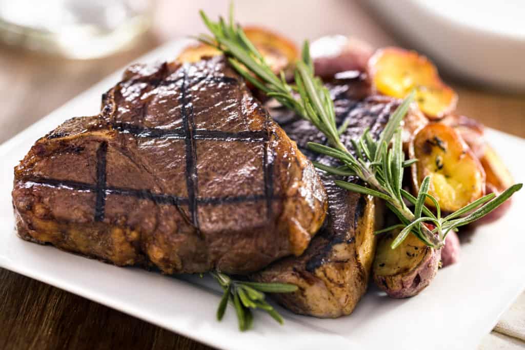 Steak on plate with roasted potatoes and rosemary garnish