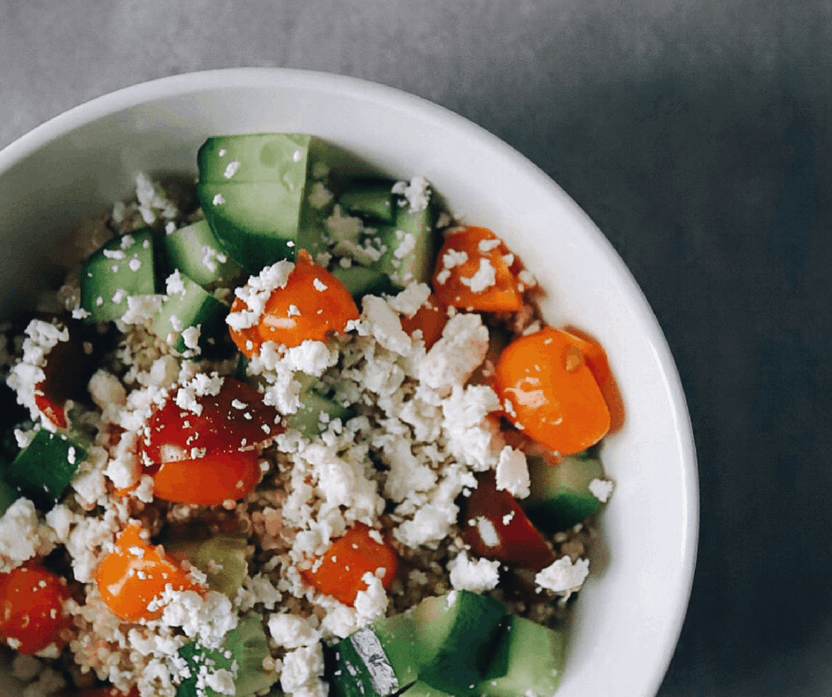 Quinoa salad topped with tomato, cucumber, and feta cheese