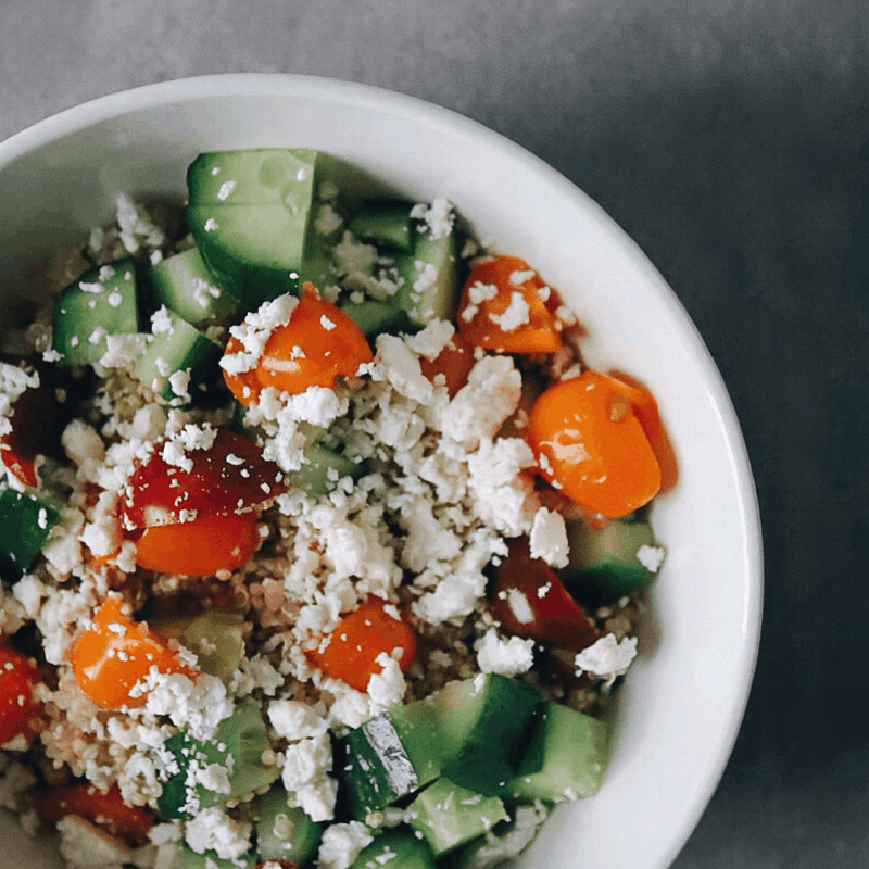 Low FODMAP Quinoa salad topped with tomato, cucumber, and feta cheese