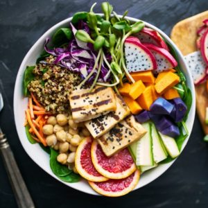 White bowl with fresh fruit, quinoa, and tofu