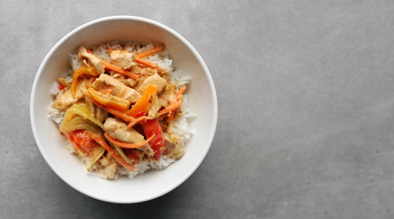 Low FODMAP Red Thai Curry in white bowl on grey surface - 810 x 450