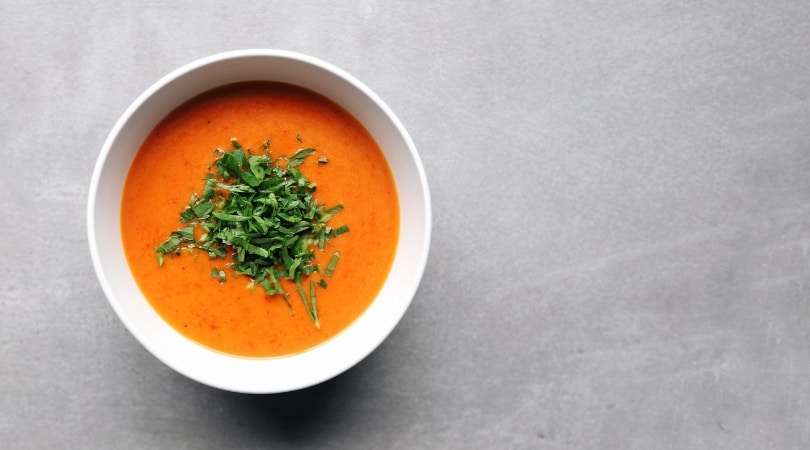 Low FODMAP Roasted Red Pepper Soup in white bowl on grey surface - 810 x 450