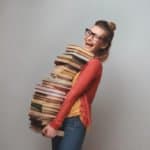 Woman holding stack of textbooks while smiling