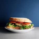 Chicken BLT sandwich on white plate with blue background - 800 x 800