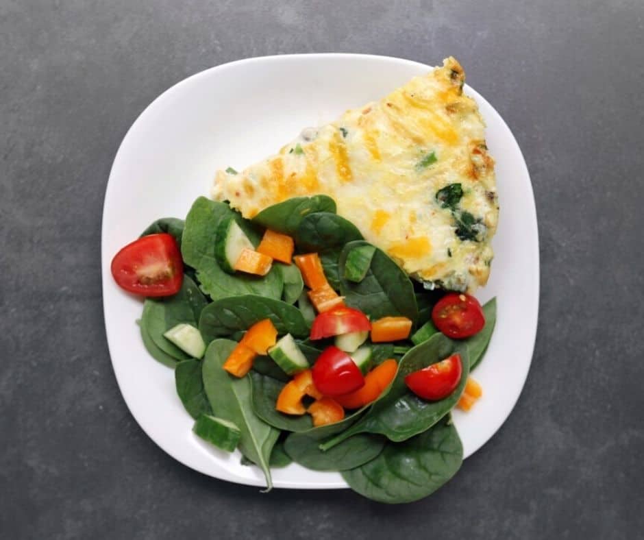 Low FODMAP vegetable frittata with vegetable salad on white plate