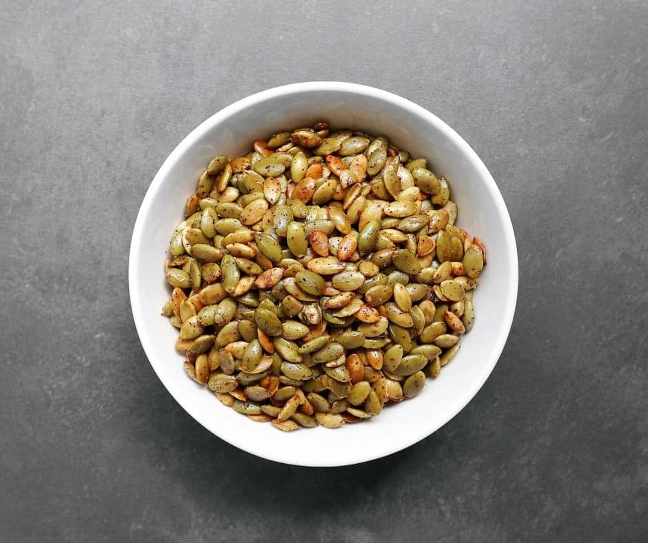 Low FODMAP roasted pumpkin seeds in white bowl