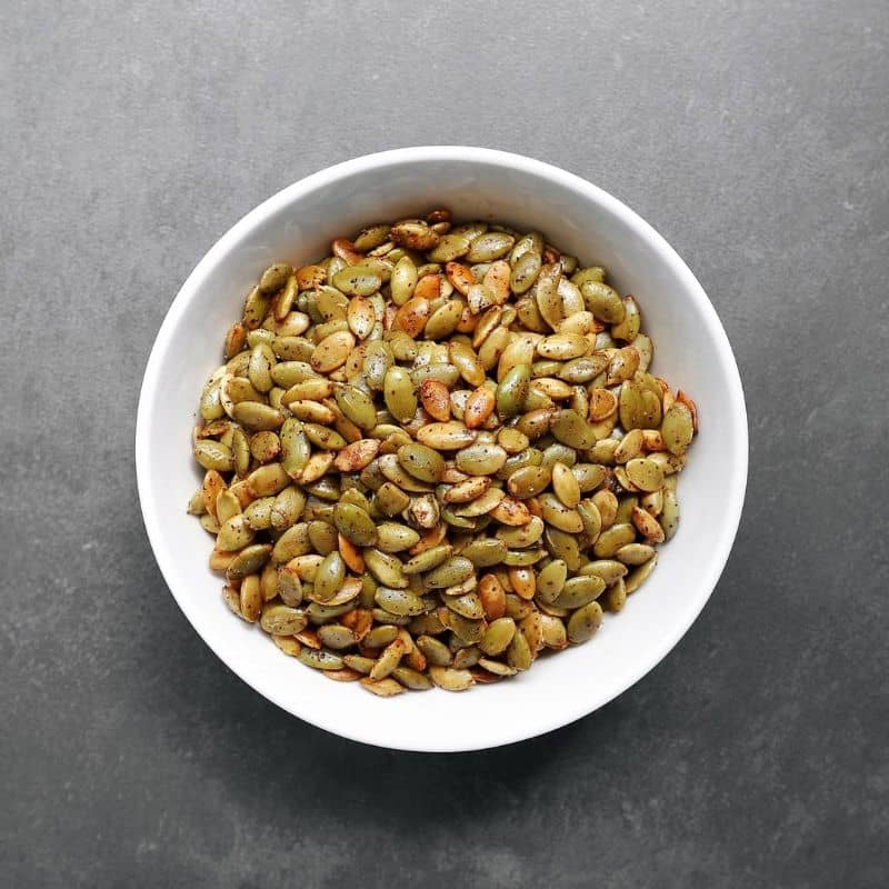 Low FODMAP roasted pumpkin seeds in white bowl