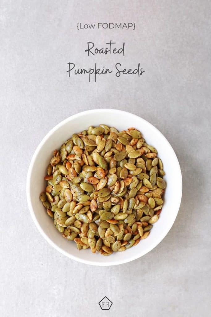 Low FODMAP roasted pumpkin seeds in white bowl with text overlayL low FODMAP roasted pumpkin seeds